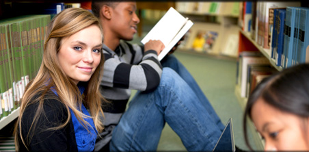 Picture of a student studying in a library with friends.